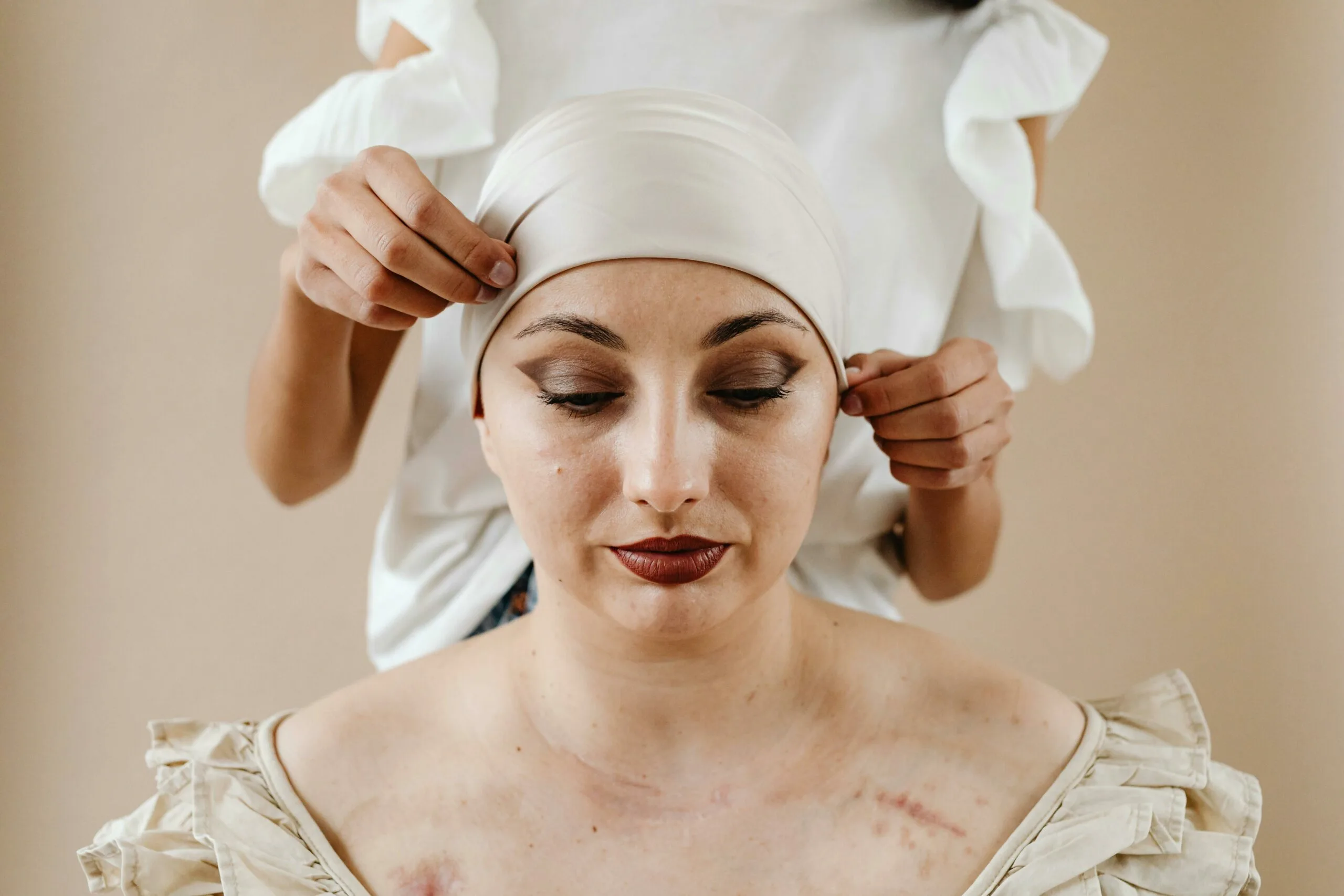 chica dejando que le pongan un turbante oncológico blanco